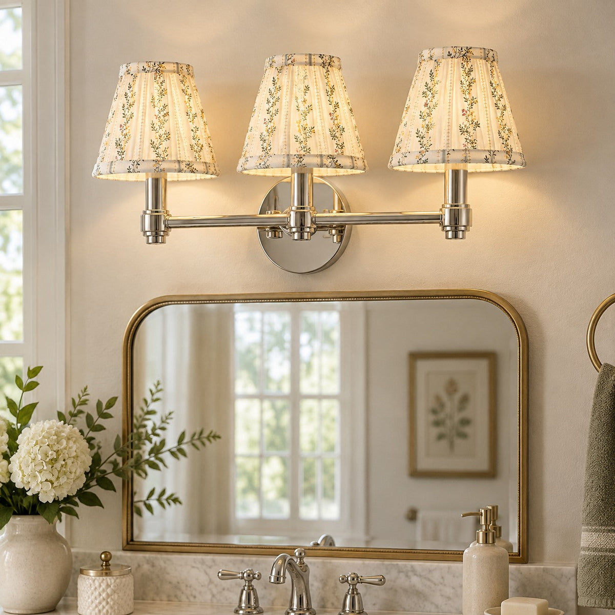 Terzetto polished nickel vanity sconce with floral print shades above a brass framed bathroom mirror