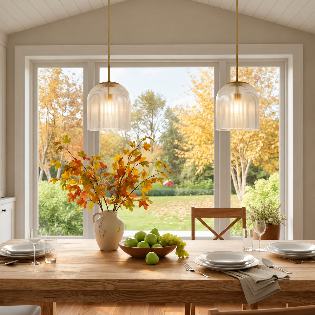 Pair of brass Rigata ribbed glass pendants over a dining table by an autumn window