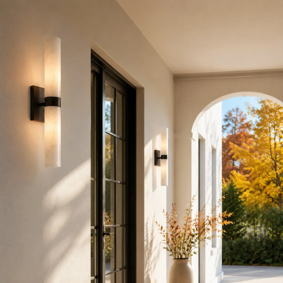 Stelo Alabastro sconce in matte black lighting a bright arched entry