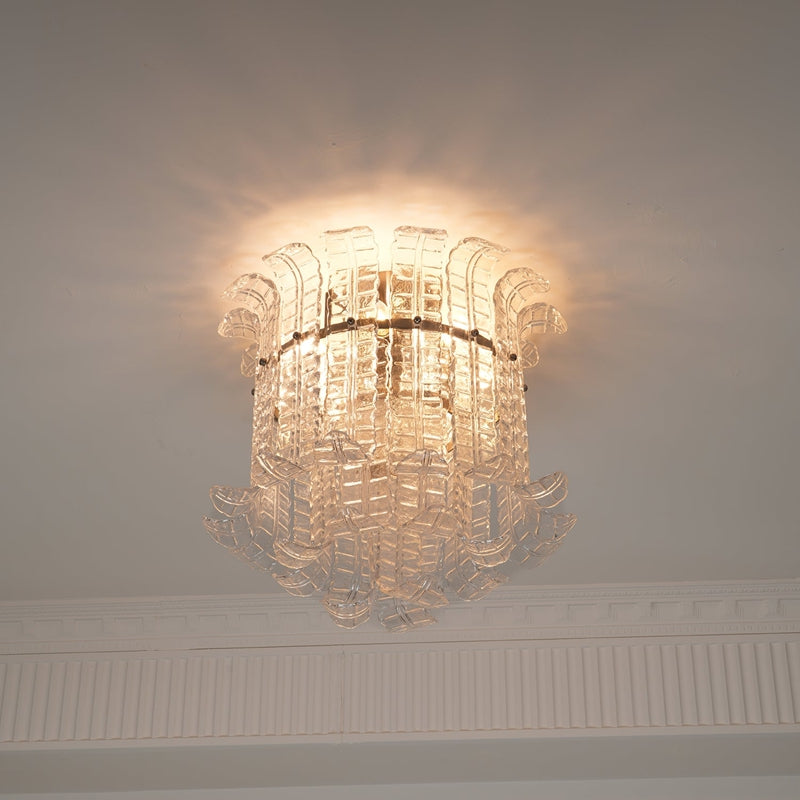 Clear glass frond flush mount ceiling light glowing warm above crown moulding