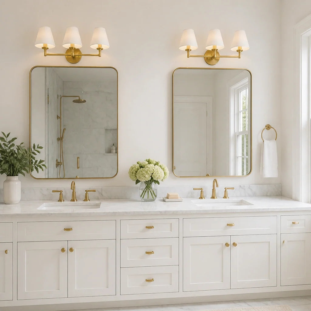Pair of Terzetto brass vanity sconces above two mirrors on a white double vanity