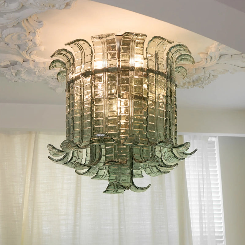 Green glass leaf flush mount ceiling light glowing beneath an ornate plaster ceiling medallion