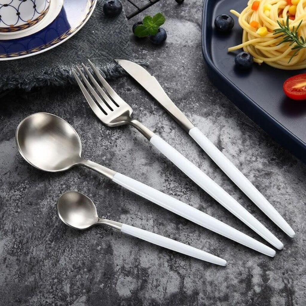 White and silver cutlery styled on a concrete surface