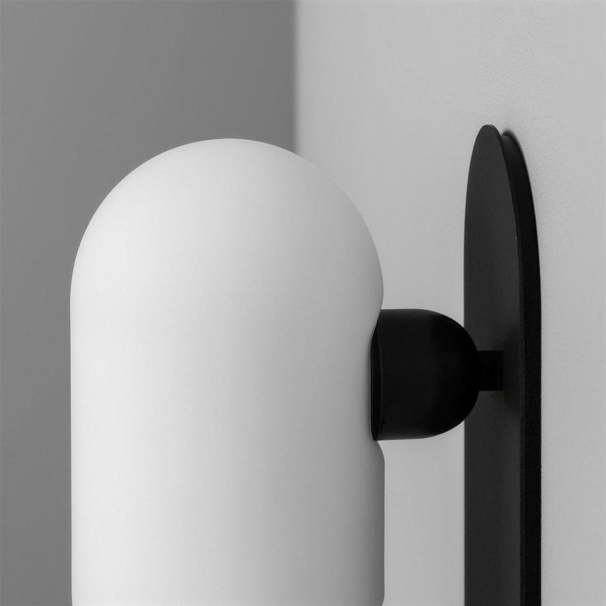 Side profile of the Capsula Opalina gunmetal wall sconce with opal glass shade