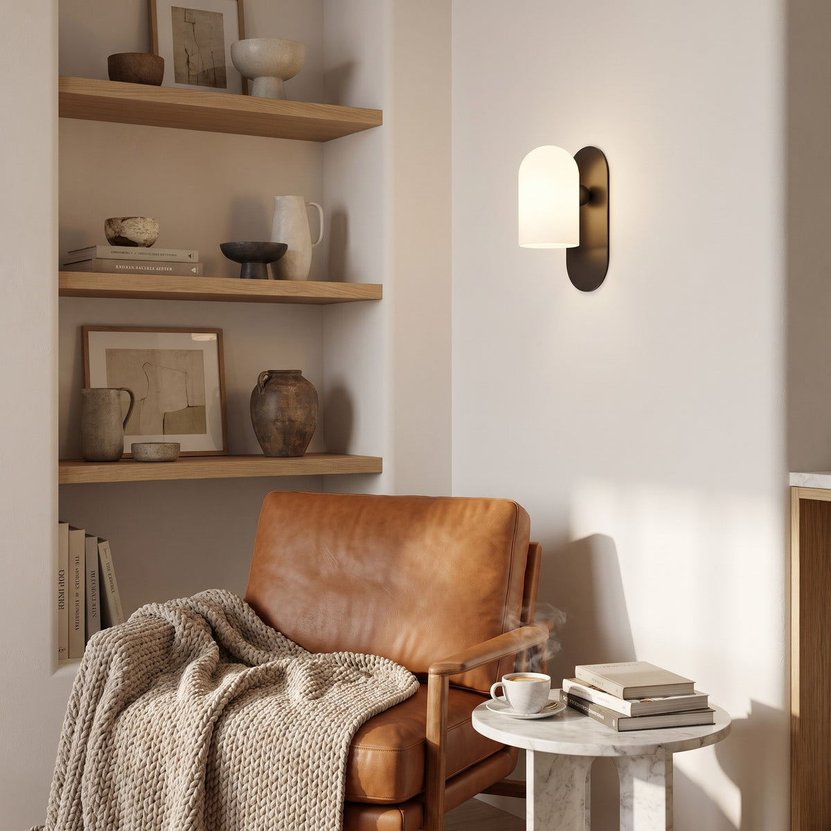 Capsula Opalina gunmetal wall sconce above a cognac leather lounge chair