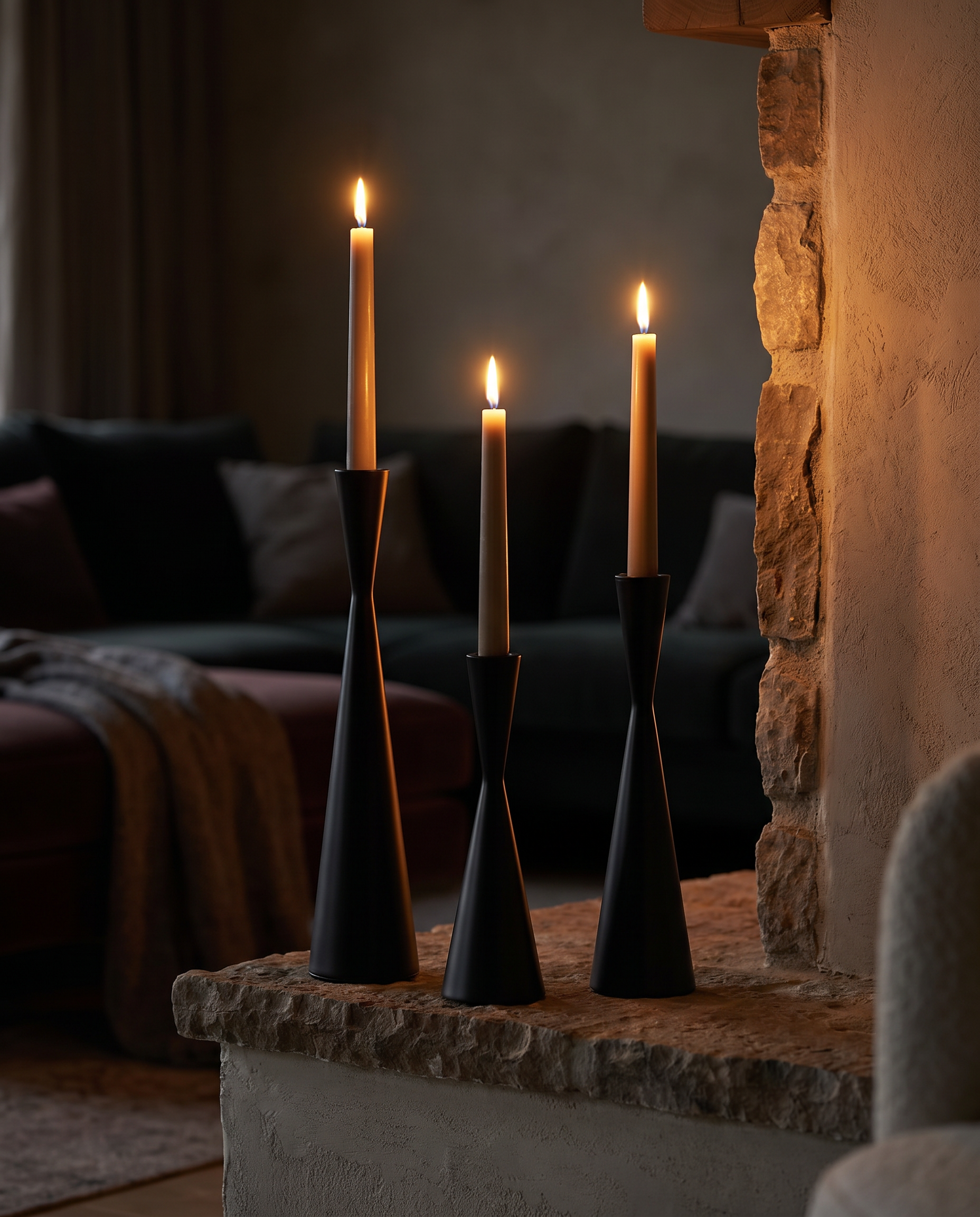 Black Fiamma Nordica candlestick trio on a fireplace mantel at dusk with lit candles