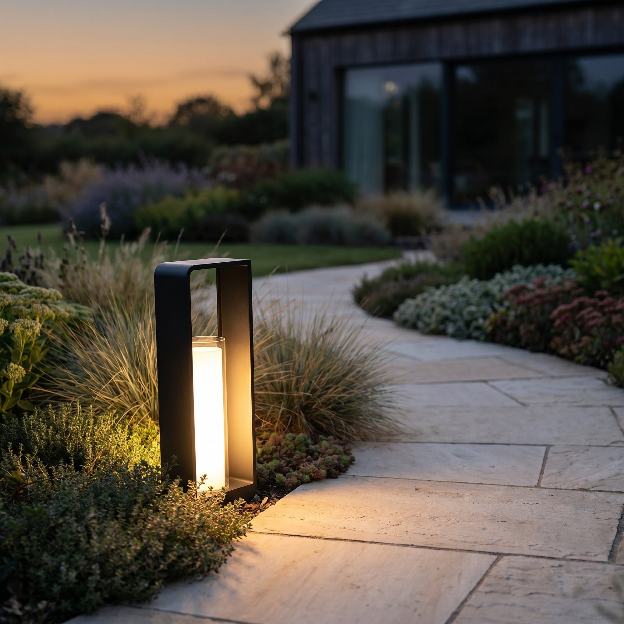 Cornice Lumina outdoor LED landscape light lining a stone garden pathway at dusk