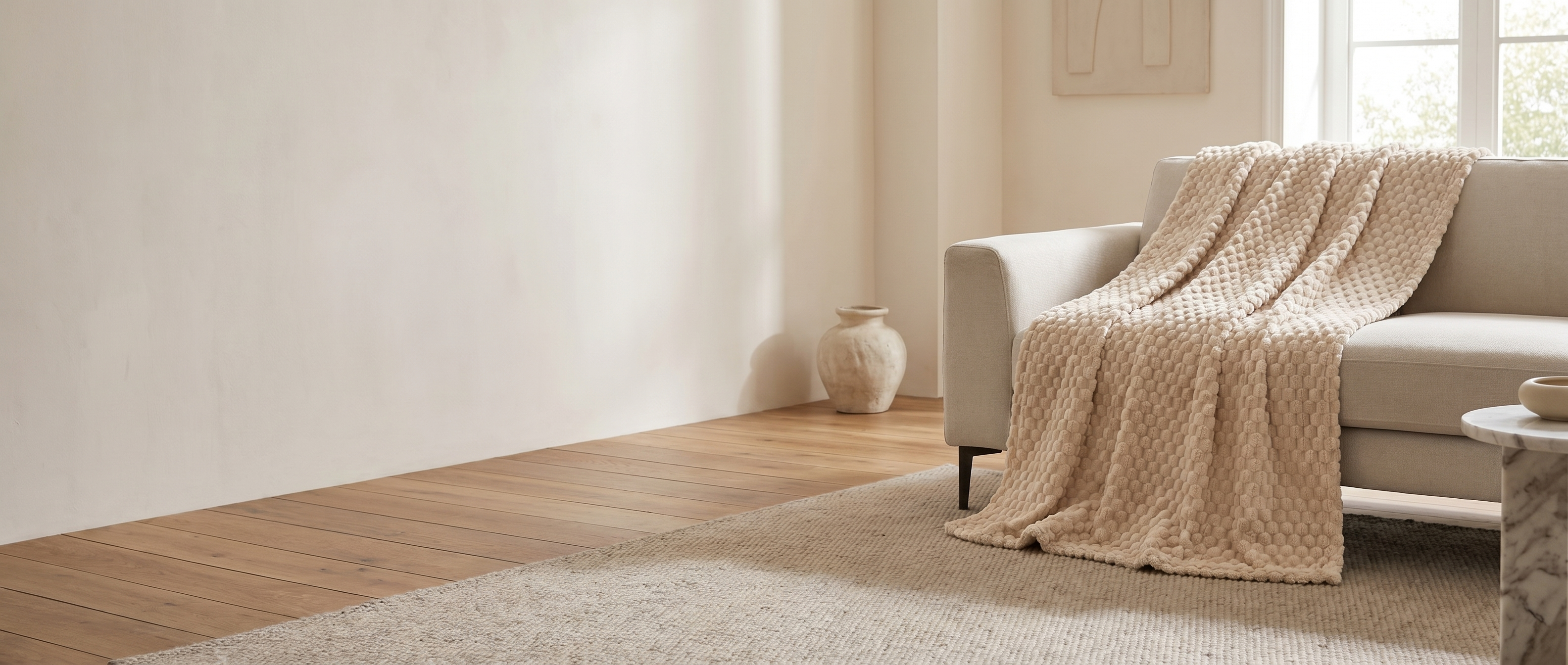 Bolla Soffice cream textured fleece throw over a sofa in a sunlit modern living room — widescreen banner