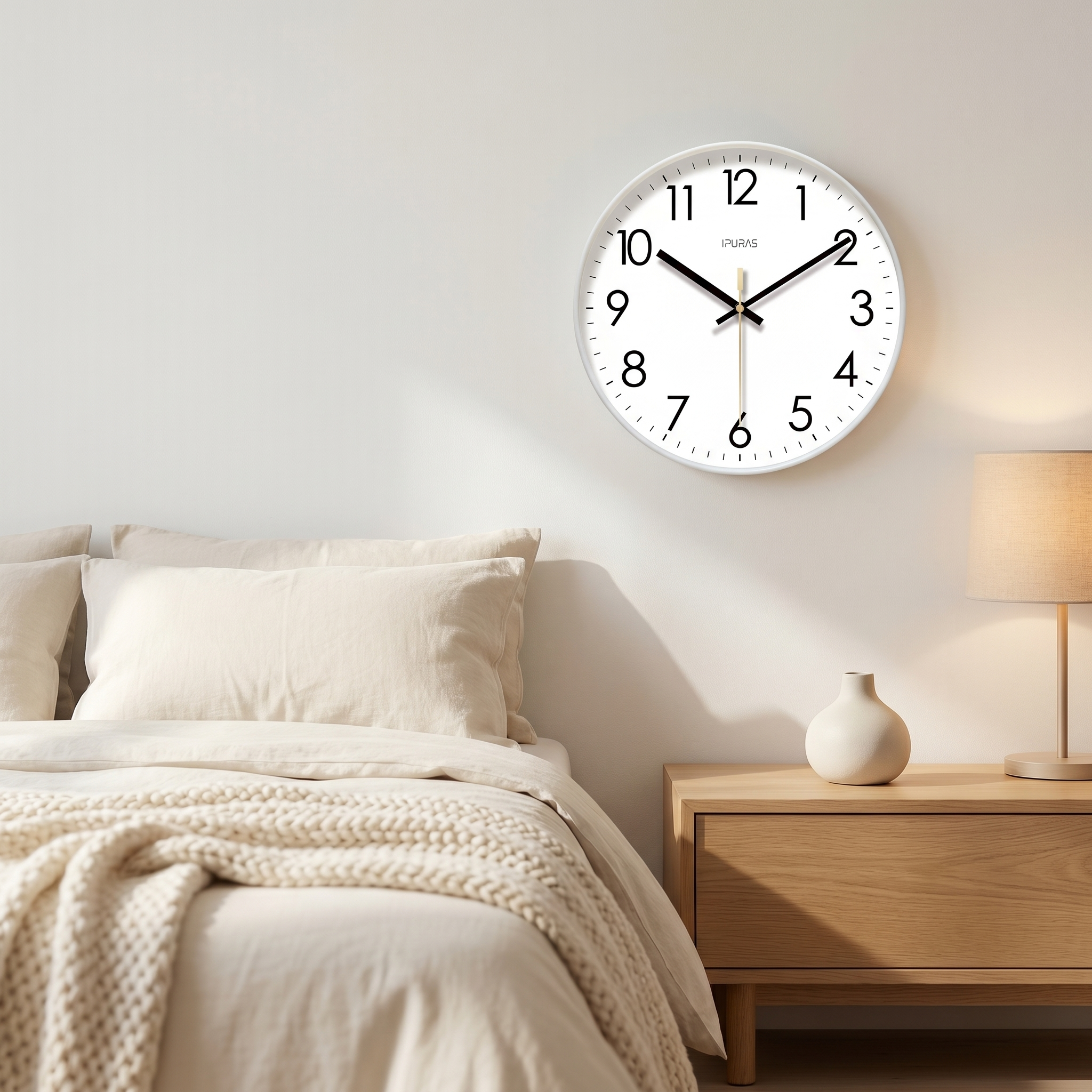 White Nordic wall clock on a serene bedroom wall above a linen bed