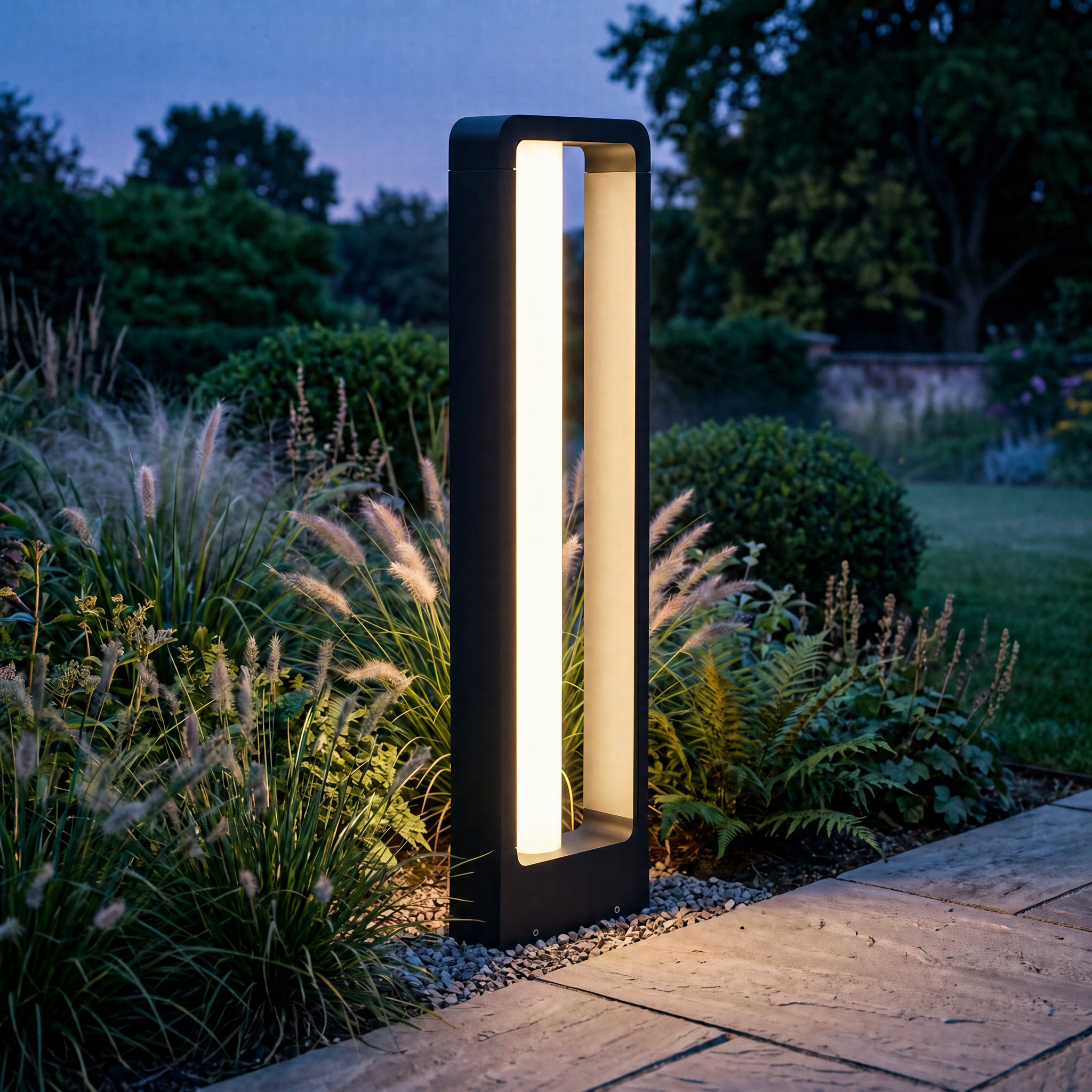 Black bollard path light glowing warm among lush ornamental garden planting