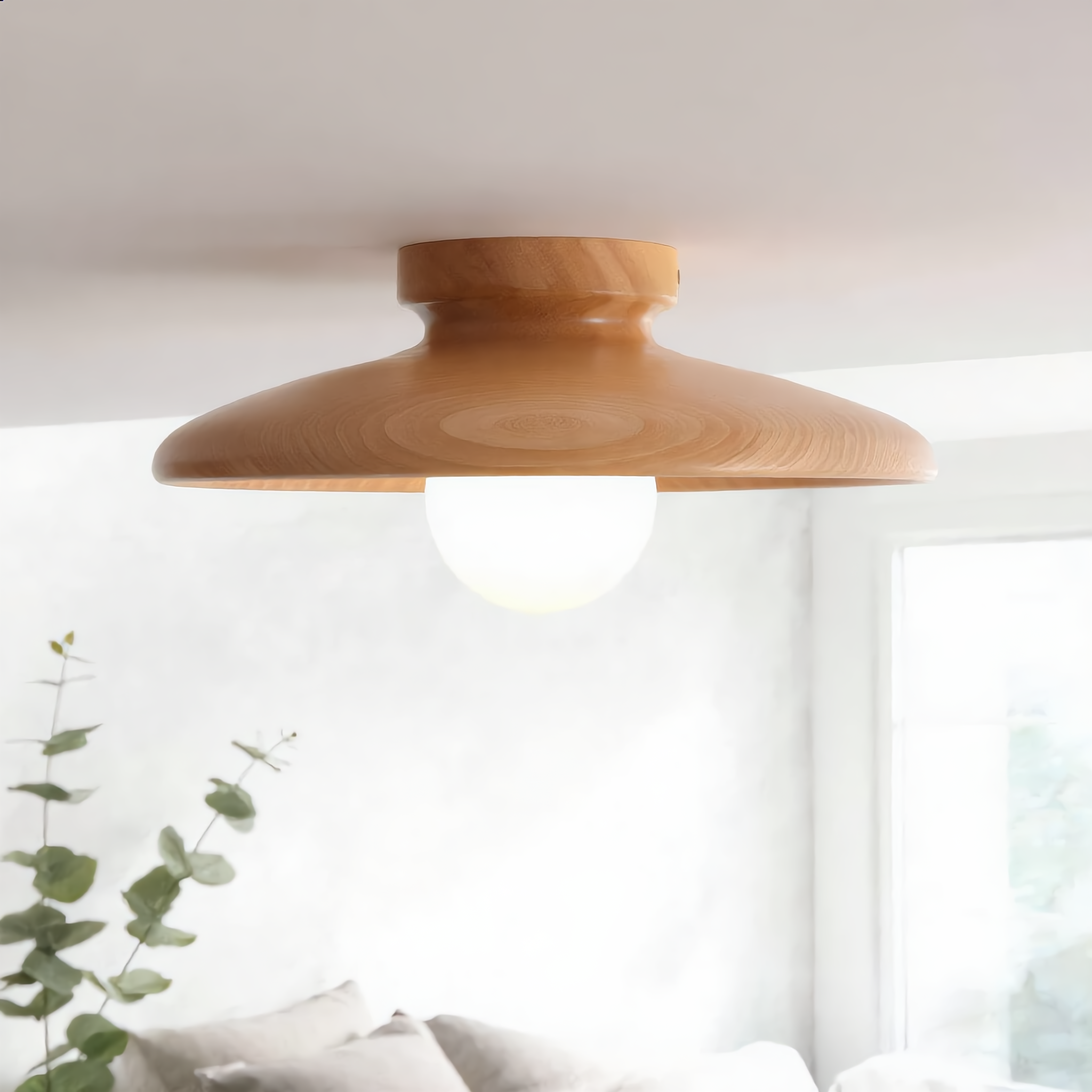 Natural wood Aureola ceiling light seen from below in a bright airy bedroom in morning light