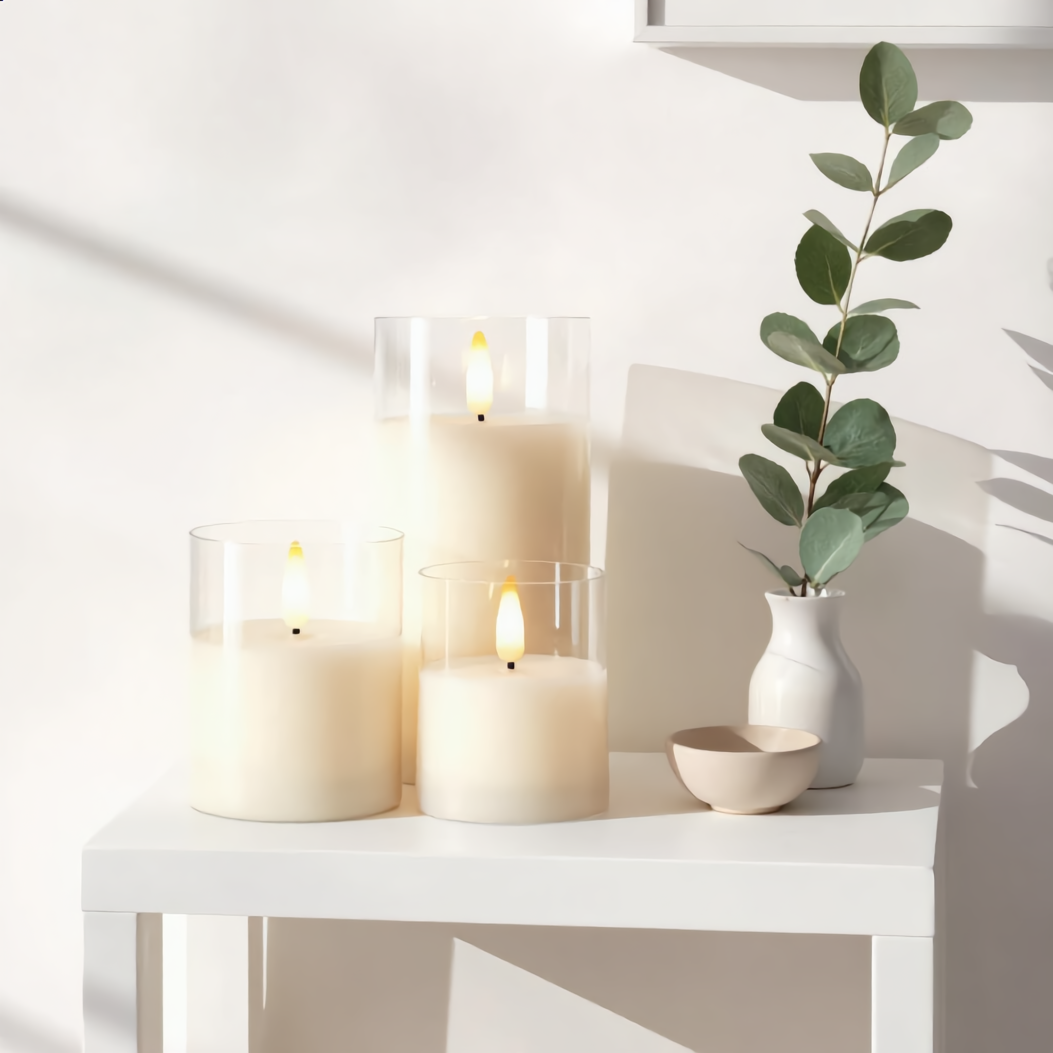 Clear glass Fiamma Serena flameless candles styled on a sunlit white console in daytime