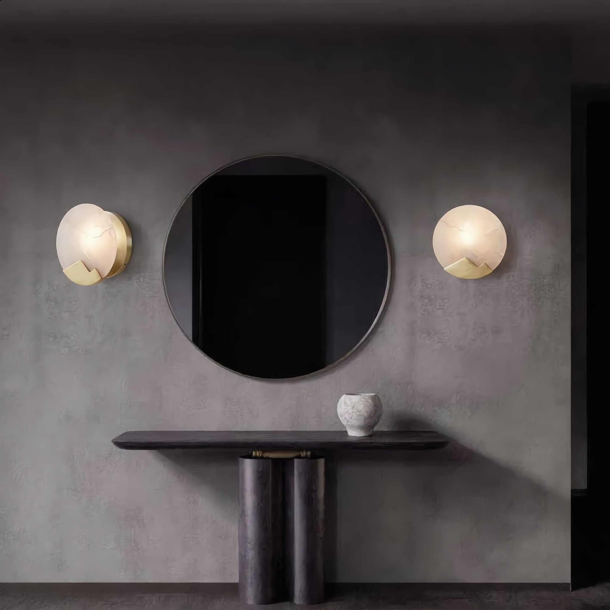 A pair of Luna d'Alabastro alabaster wall sconces flanking a round mirror on a feature wall
