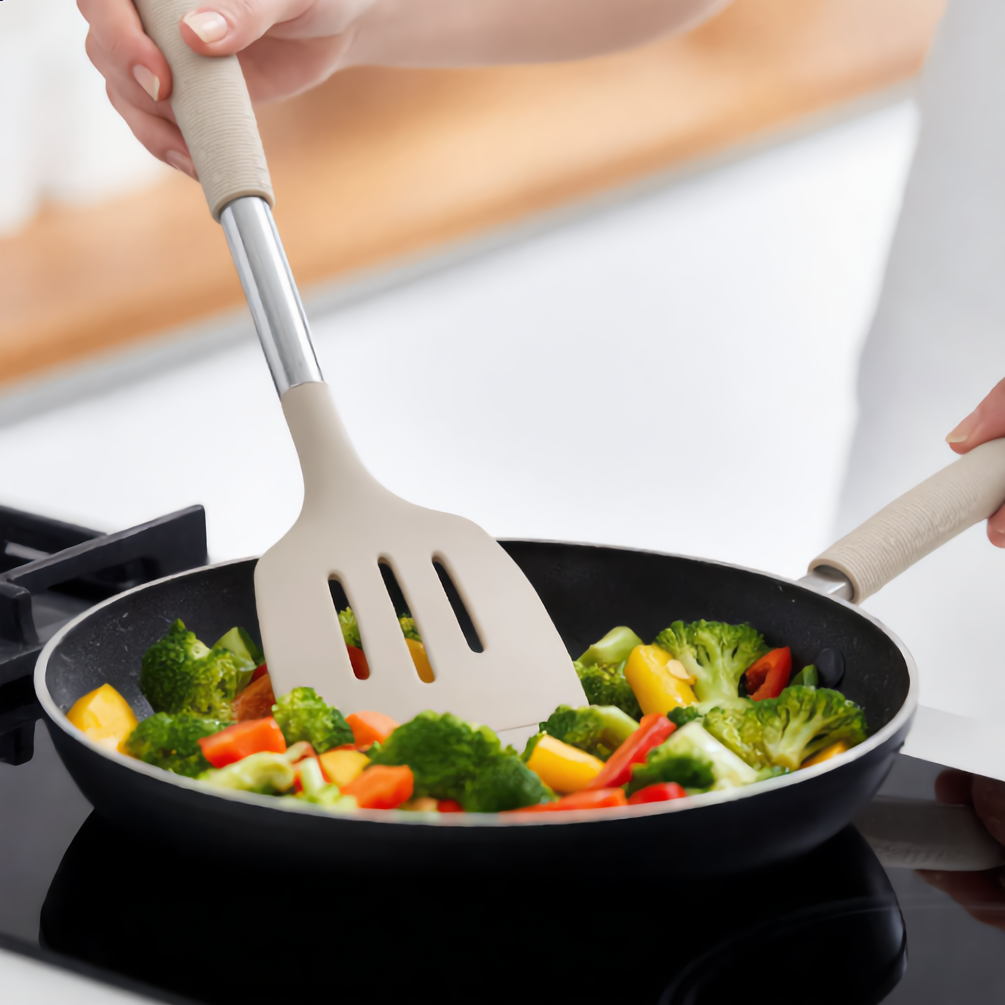 Khaki Nordica slotted turner stirring fresh vegetables in a pan