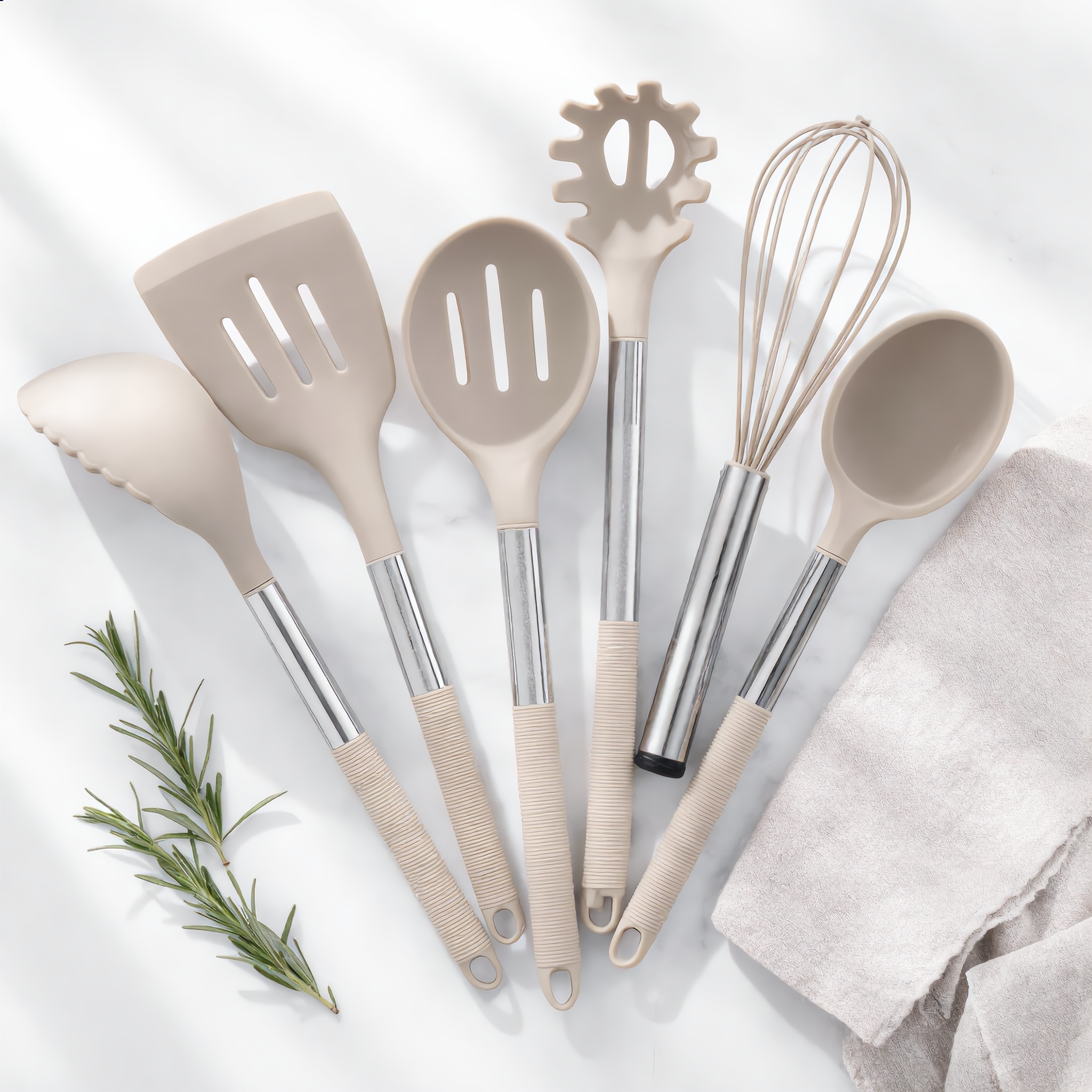 Khaki Nordica utensils flat-lay on marble with rosemary and linen
