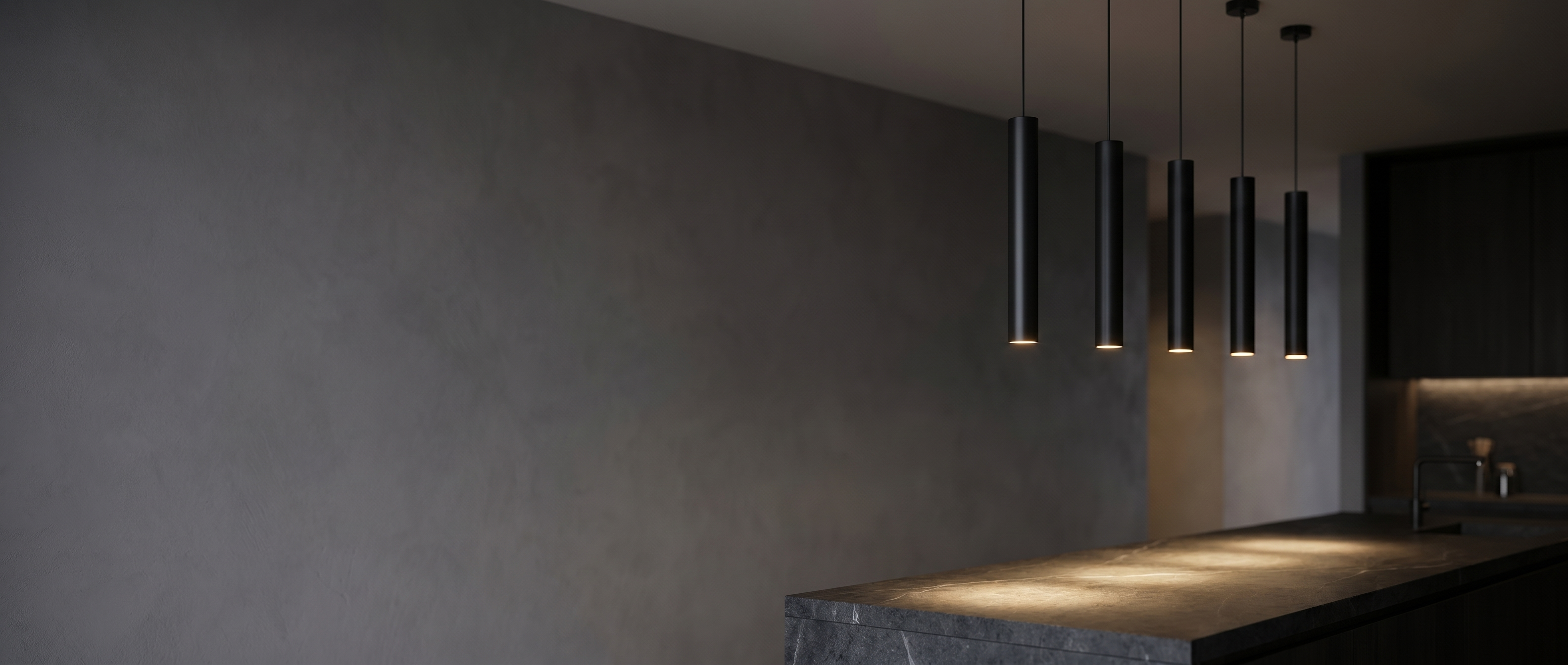 Flauto Slim Tube Pendants glowing over a stone kitchen island at dusk