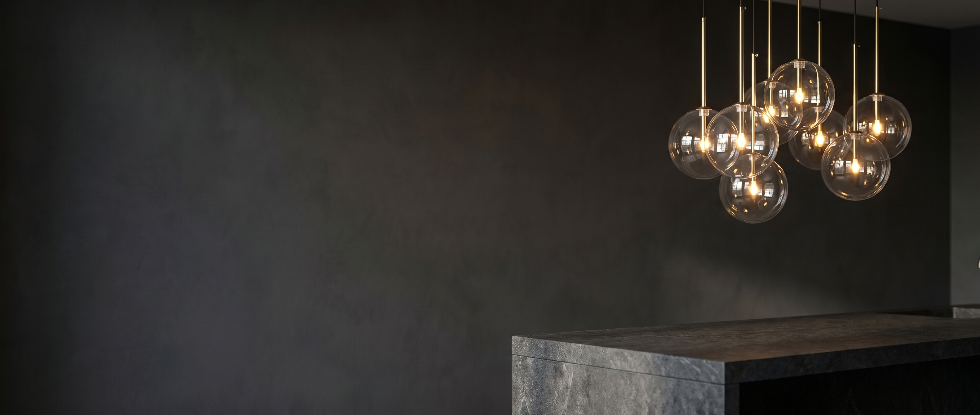Goccia clear glass ball pendants glowing warmly over a kitchen island at dusk