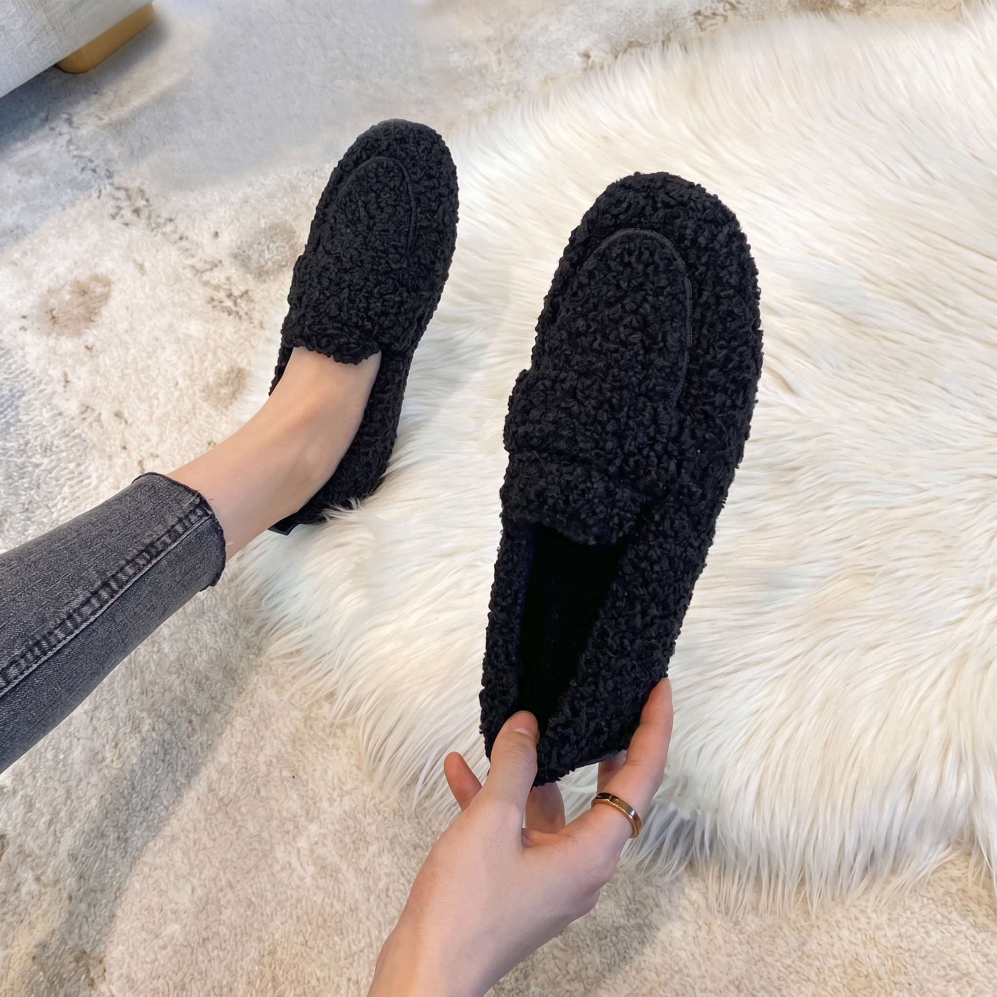 Black plush teddy slippers worn on a soft fur rug