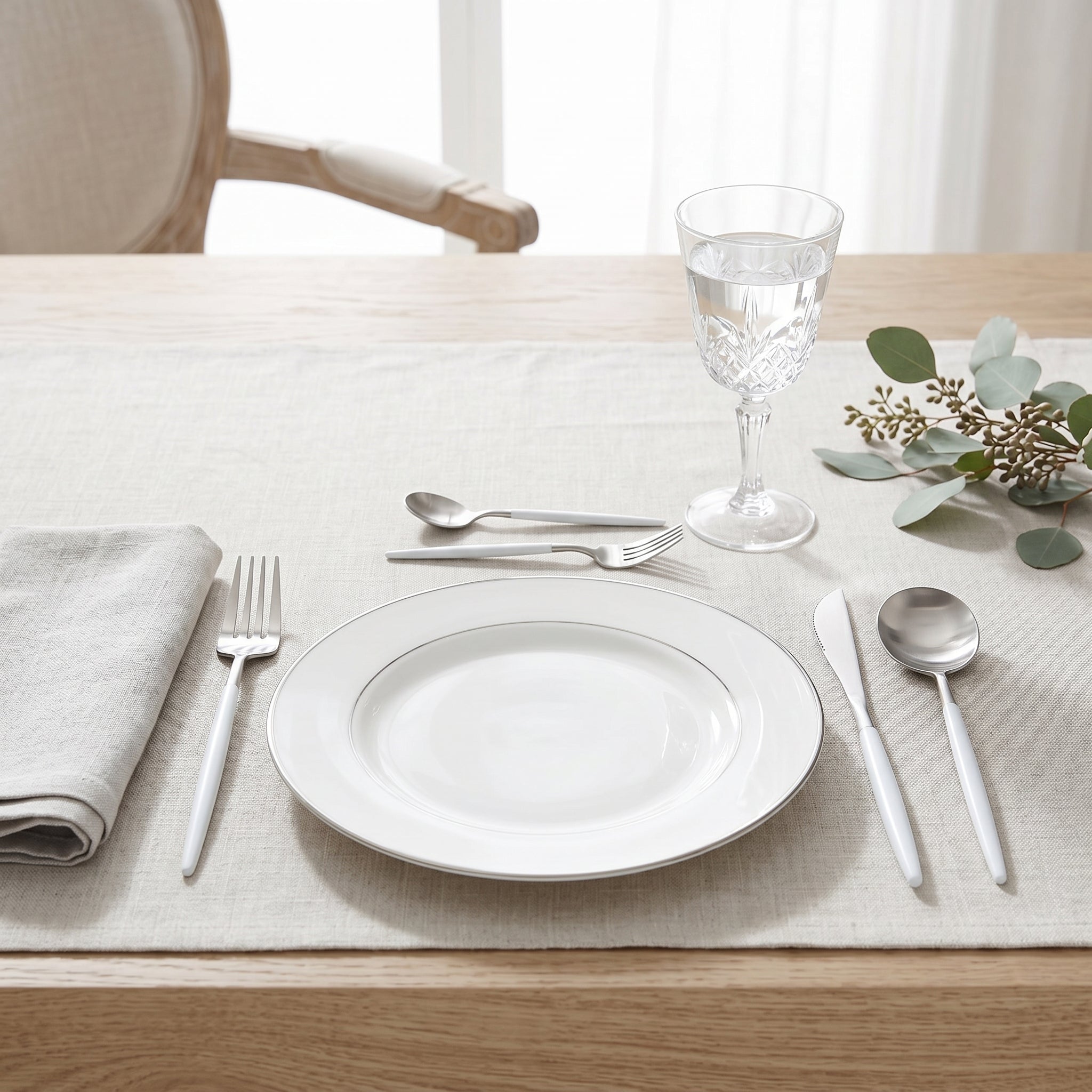 White and silver cutlery in an elegant place setting with eucalyptus