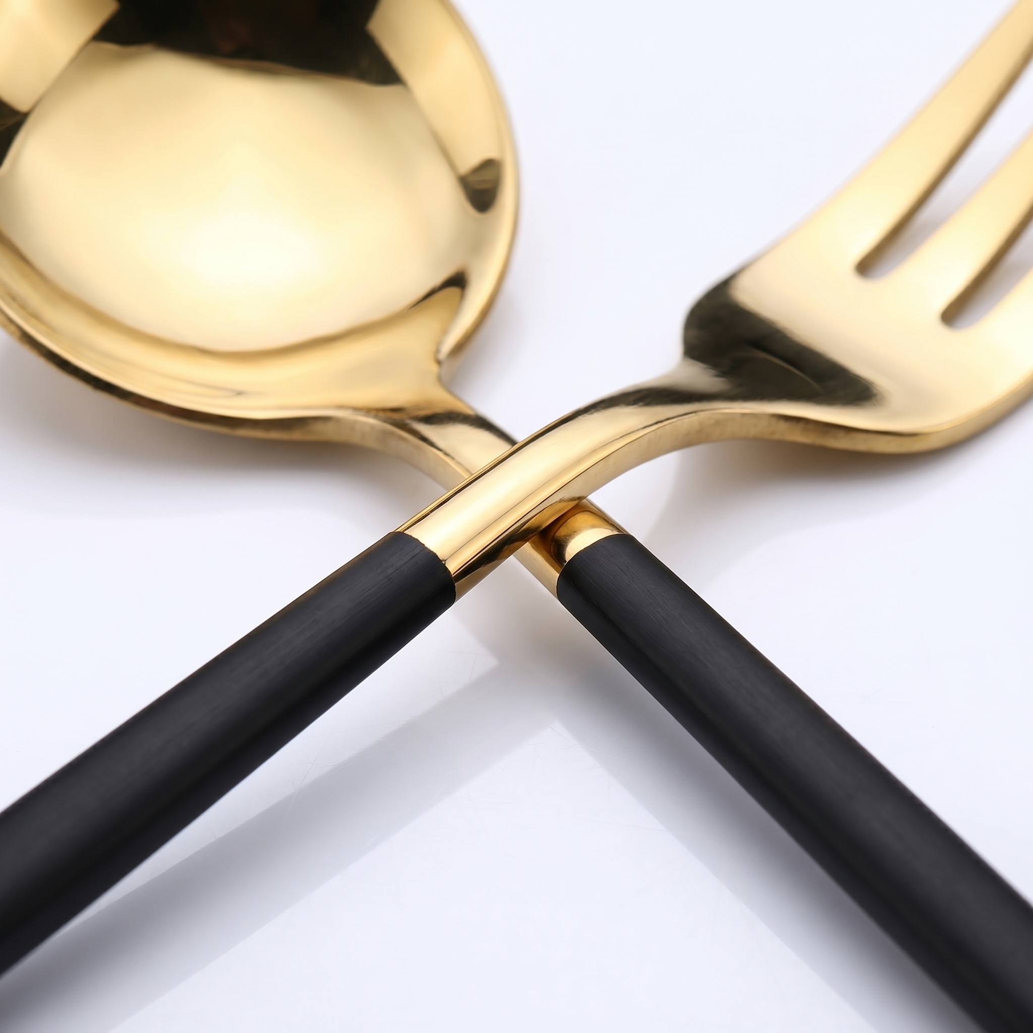 Macro detail of polished gold head and black handle two-tone flatware