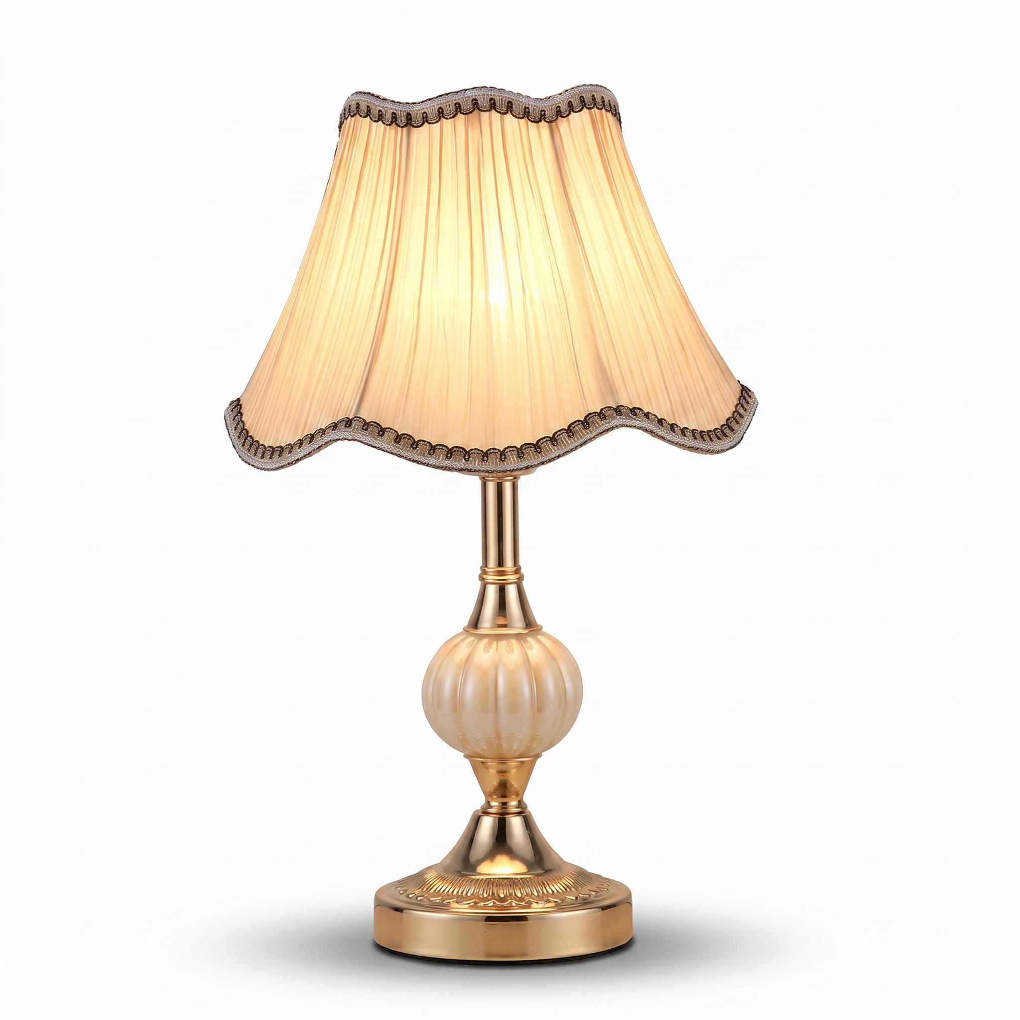 Vintage table lamp with gold base and cream pleated shade on white background