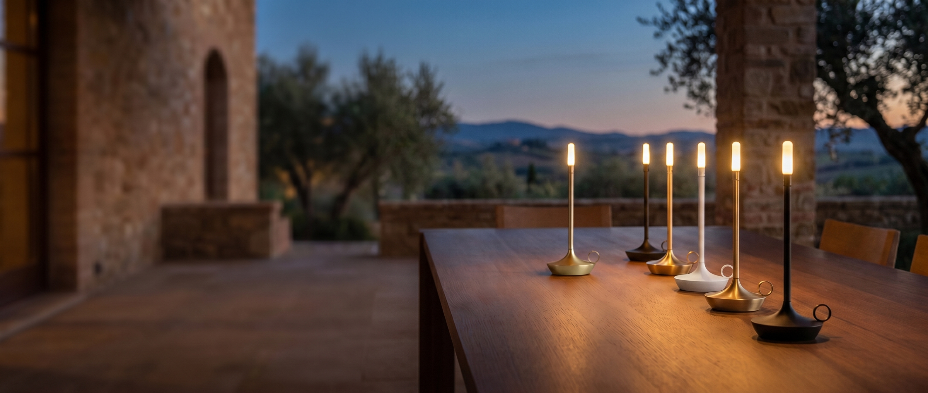 Fiamma cordless candle lamps glowing on a table at dusk