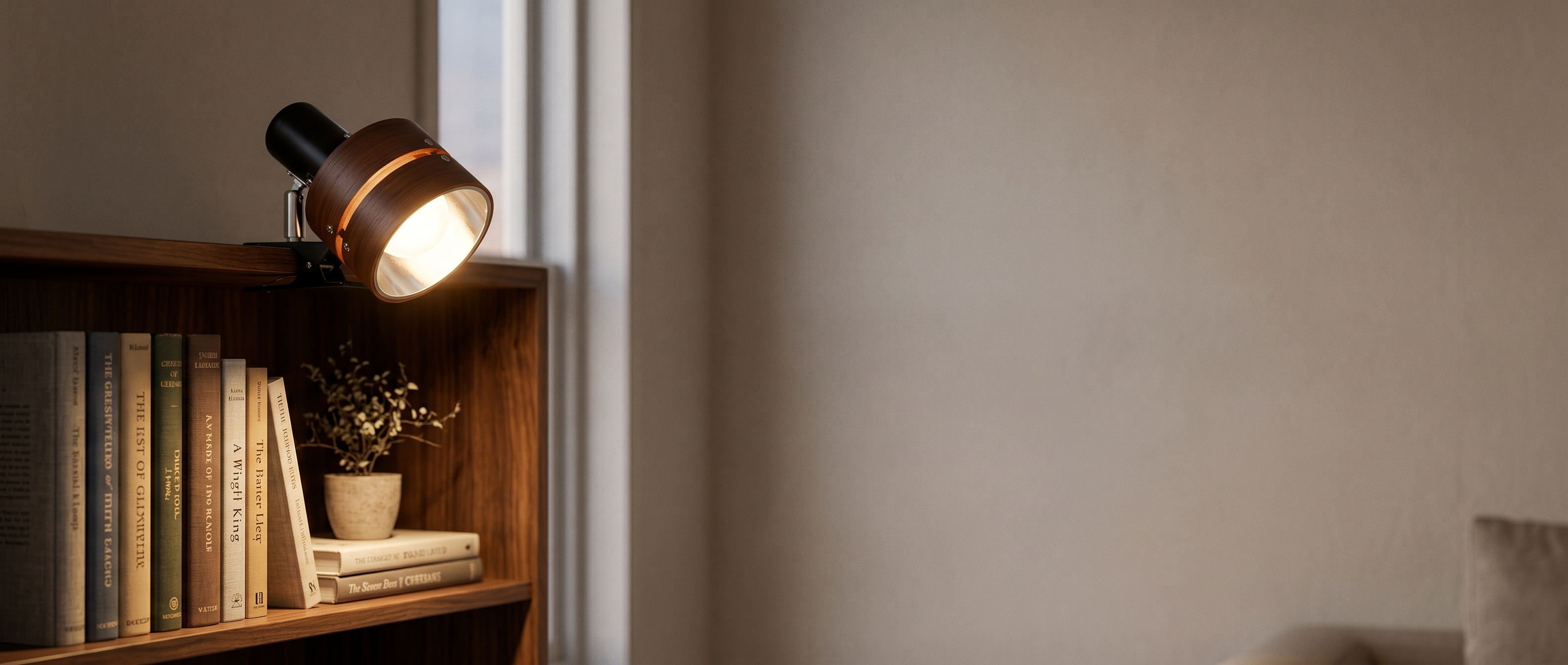 Bosco wood clip reading lamp glowing on a bookshelf banner