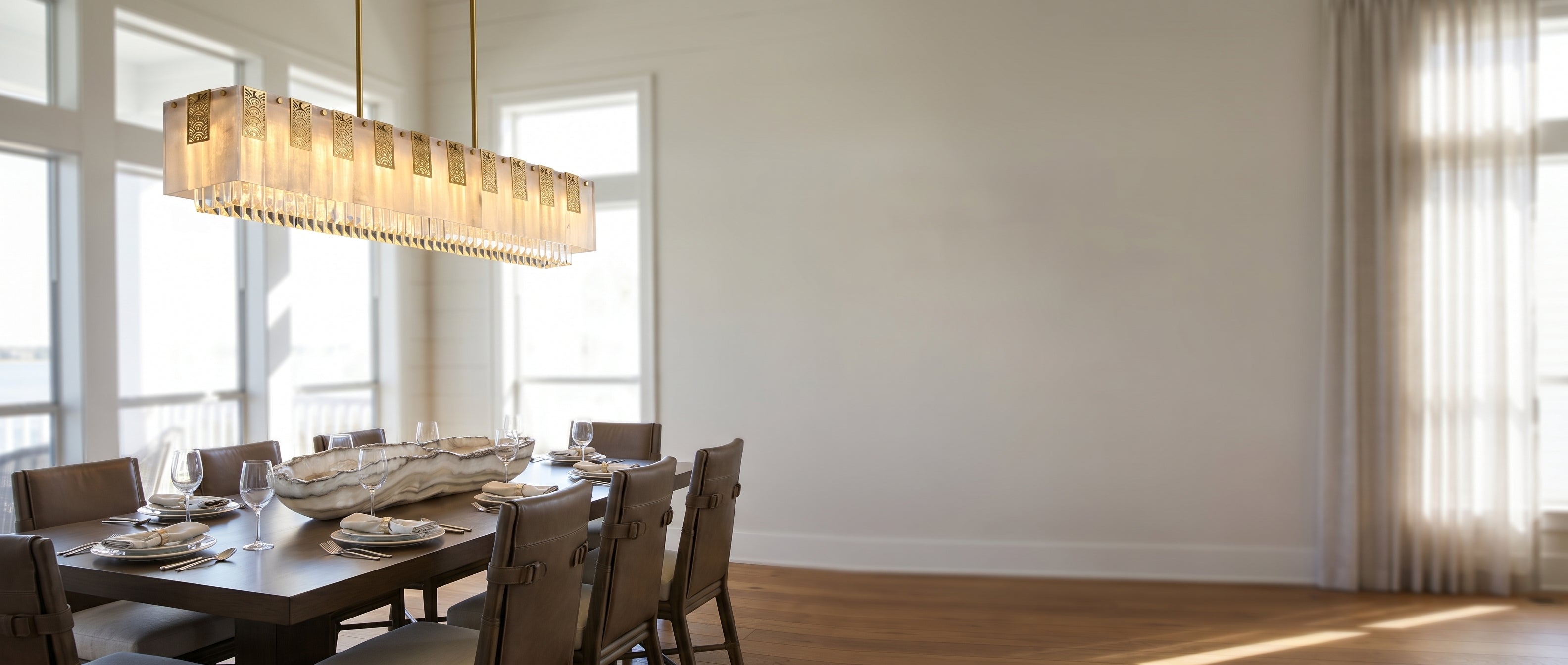 Cascata Brillante gold crystal bar pendant glowing over a dining table in a luxury room