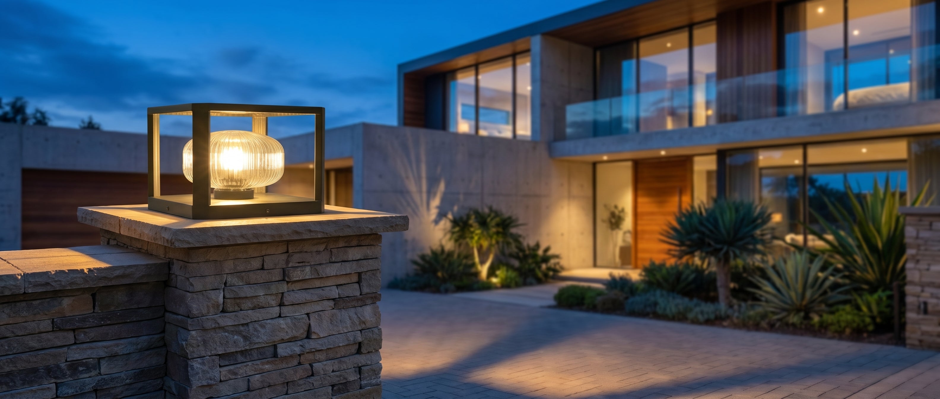 Sera Dorata solar pillar light glowing on a stone gate pillar at a modern villa at blue-hour