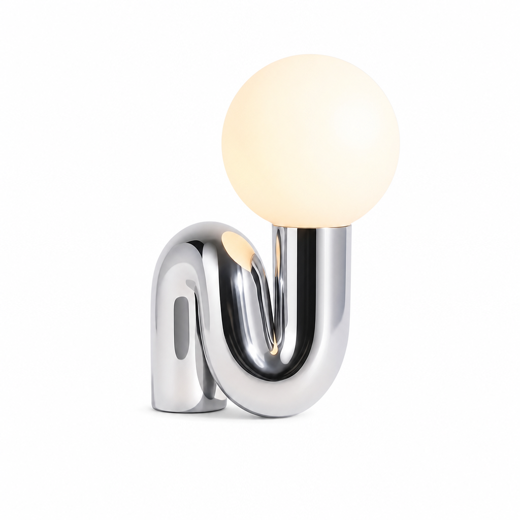 Ricciolo Lucente chrome sculptural table lamp with frosted glass globe glowing warm, on white