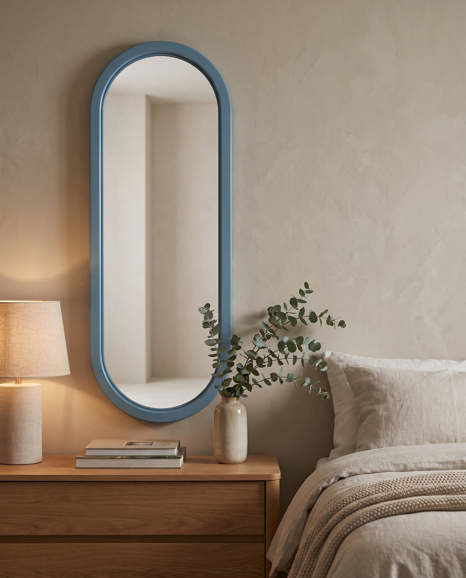 Ovale Azzurro capsule wall mirror above a bedroom dresser