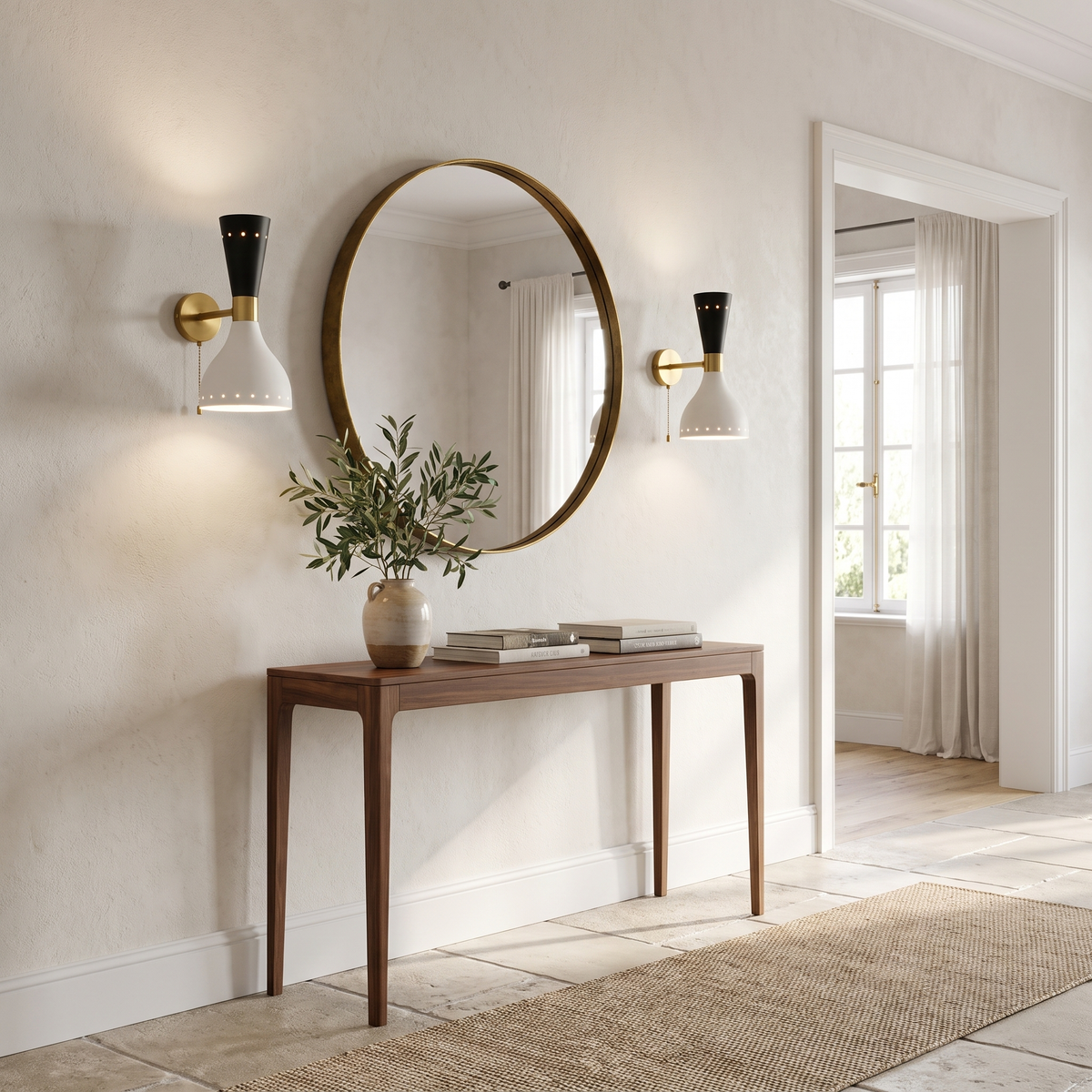 Pair of brass wall sconces beside a round mirror in a bright entry hall