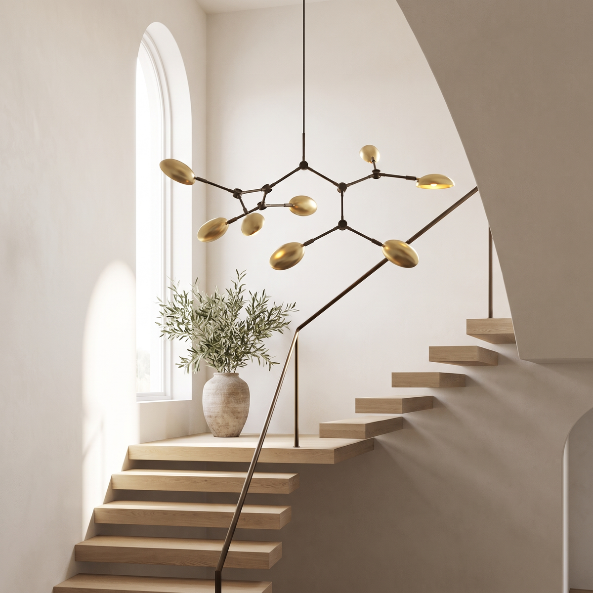 Ramo Goccia brass branch chandelier hanging in a bright open stairwell