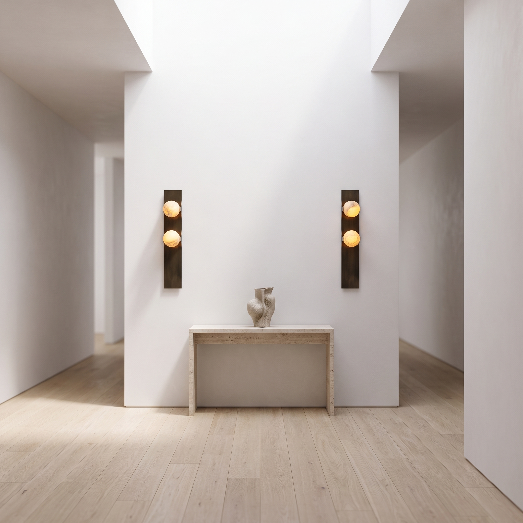 Brass double alabaster wall sconces flanking a travertine console in a bright gallery hallway