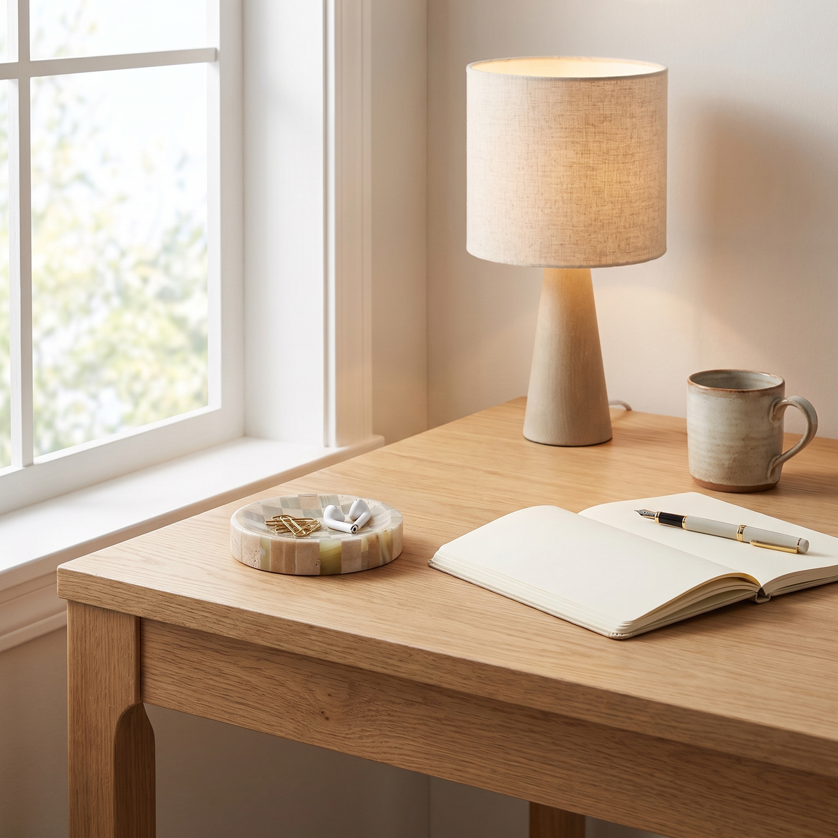Olvera stone dish holding desk essentials on a light oak desk