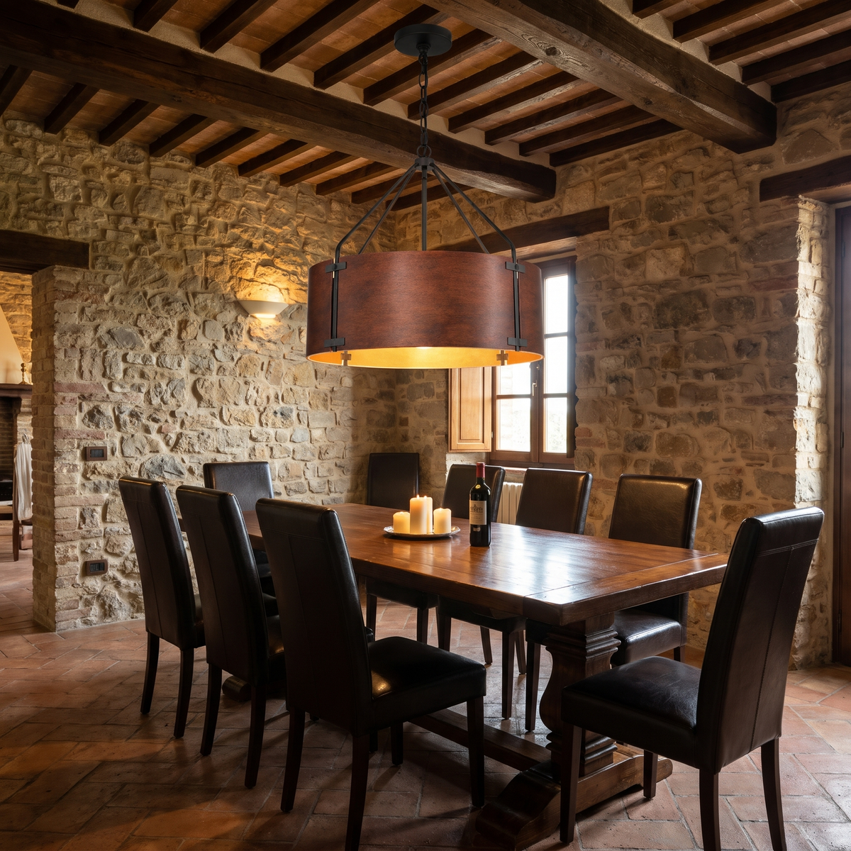 Large Tamburo bronze drum chandelier over a table in a Tuscan stone dining room