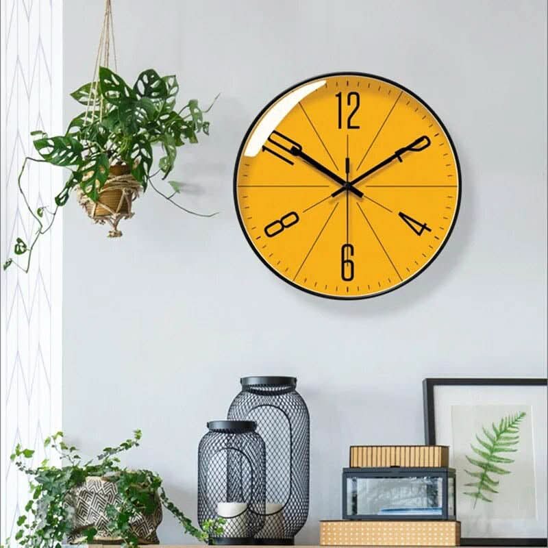 Orange Nordic wall clock on a wall with a hanging plant