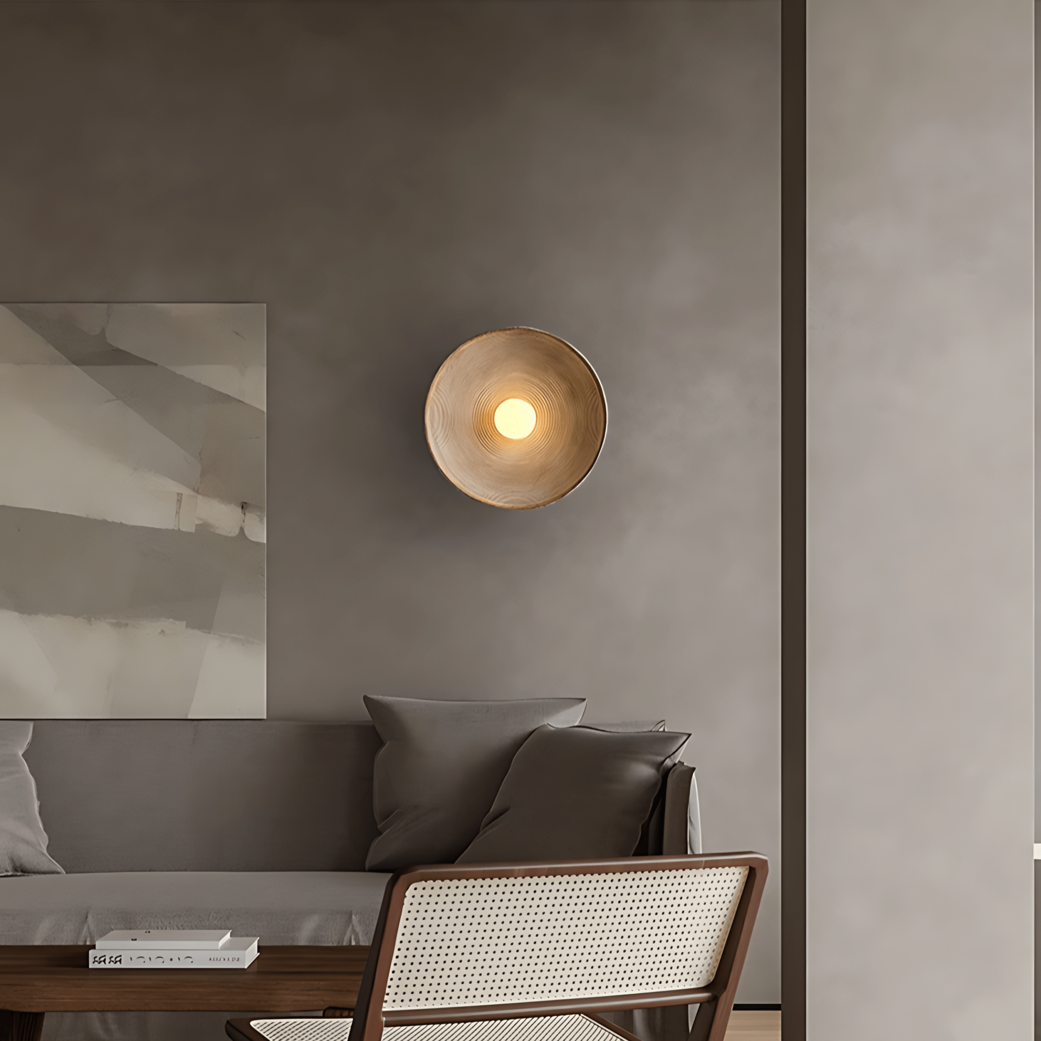 Aurelia Sculptural Wall Sconce above a grey sofa beside abstract art