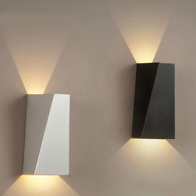 Faccetta Aurora geometric up down wall sconce in white and black glowing on a wall