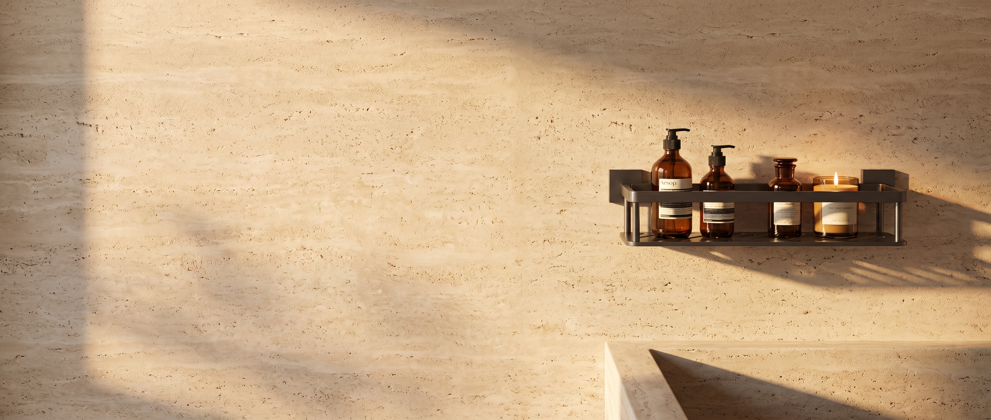 Gunmetal Sospesa shelf with amber bottles and a candle on a sunlit travertine wall