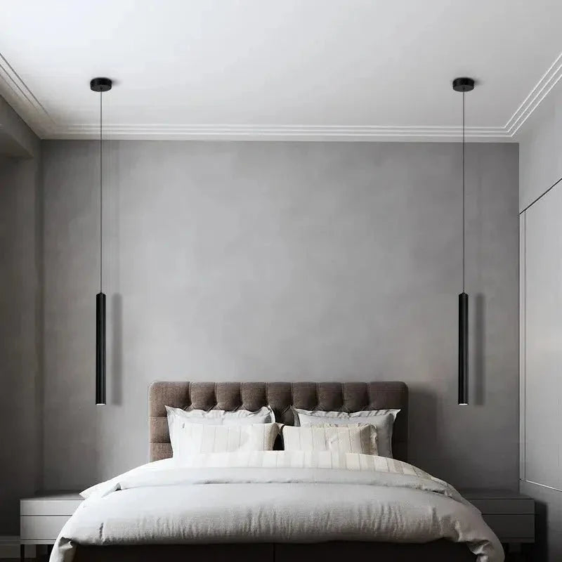 A pair of black Flauto tube pendants flanking a bed with a ceiling rose