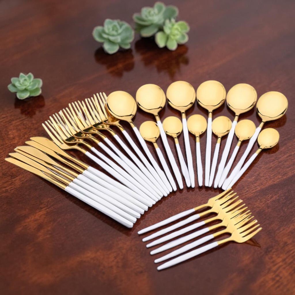 Full white and gold cutlery set arranged on a table