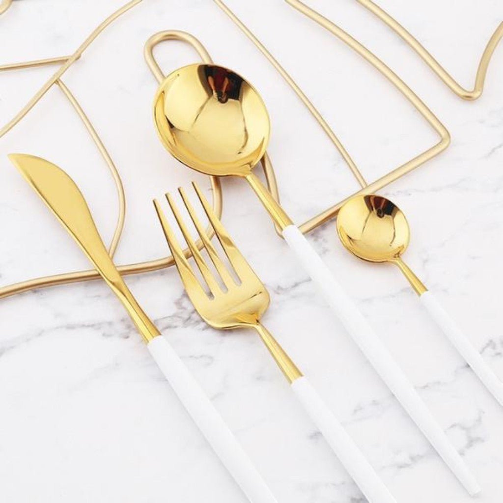 White and gold cutlery flat lay on marble