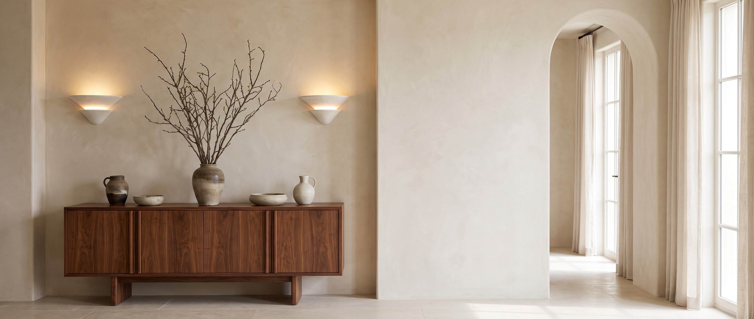 Pair of Coppa Serena alabaster wall sconces above a walnut console in a bright entrance hall