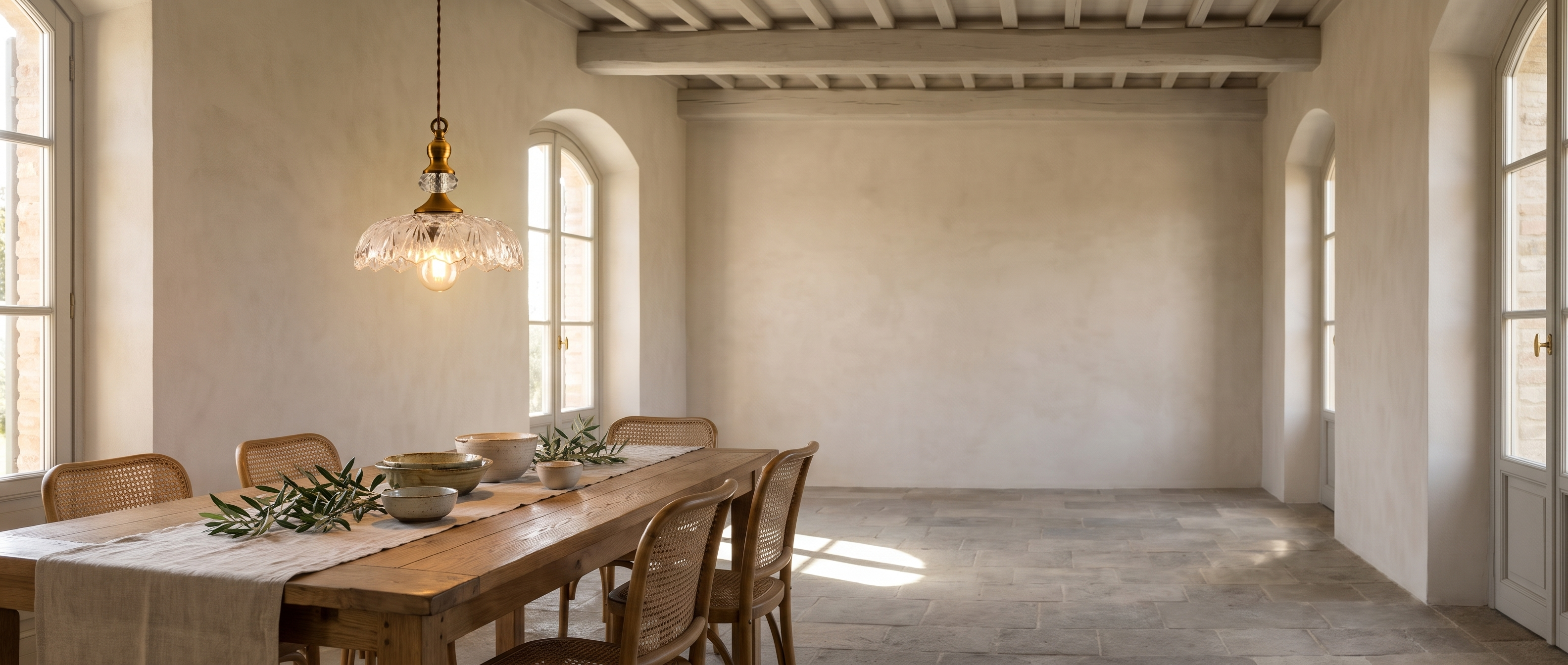 Clear glass and brass flower pendant above a long farmhouse table