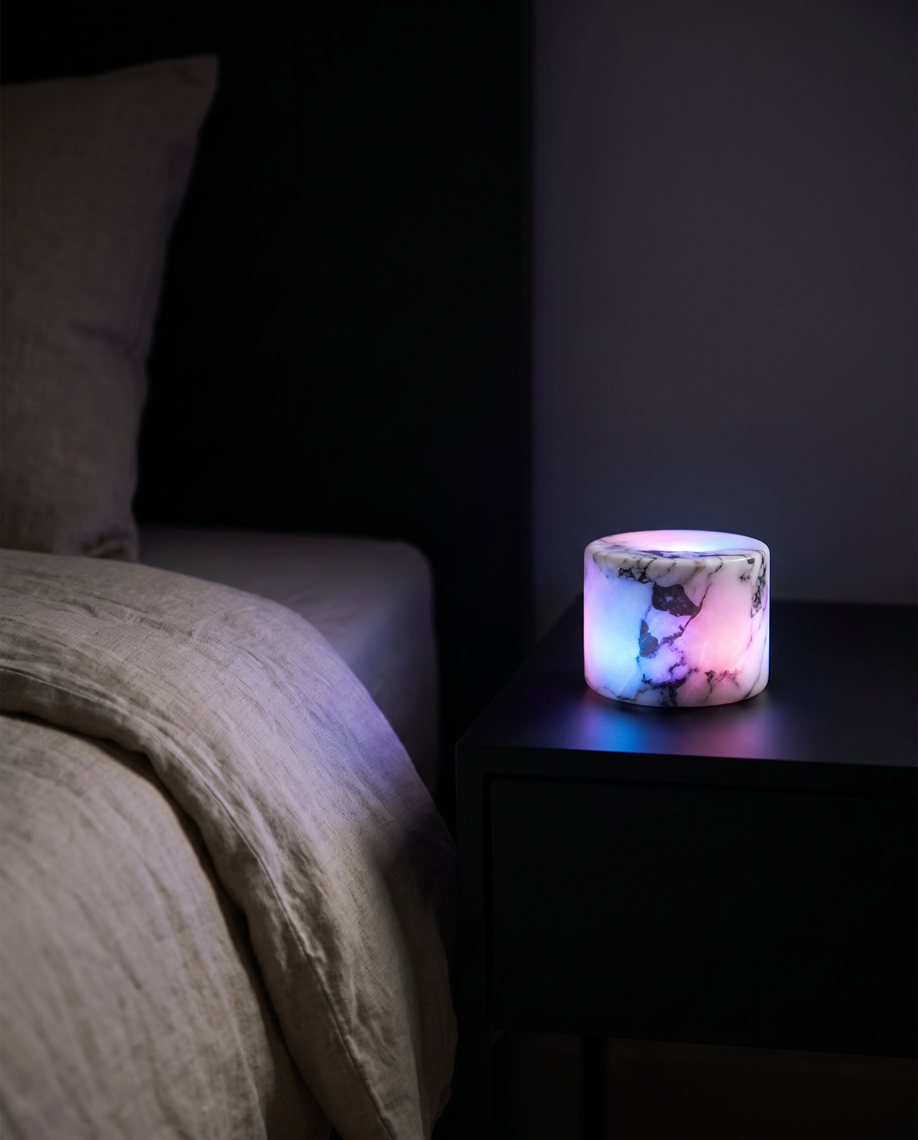 Marble mood lamp glowing multicolor RGB in a dark minimalist bedroom at night