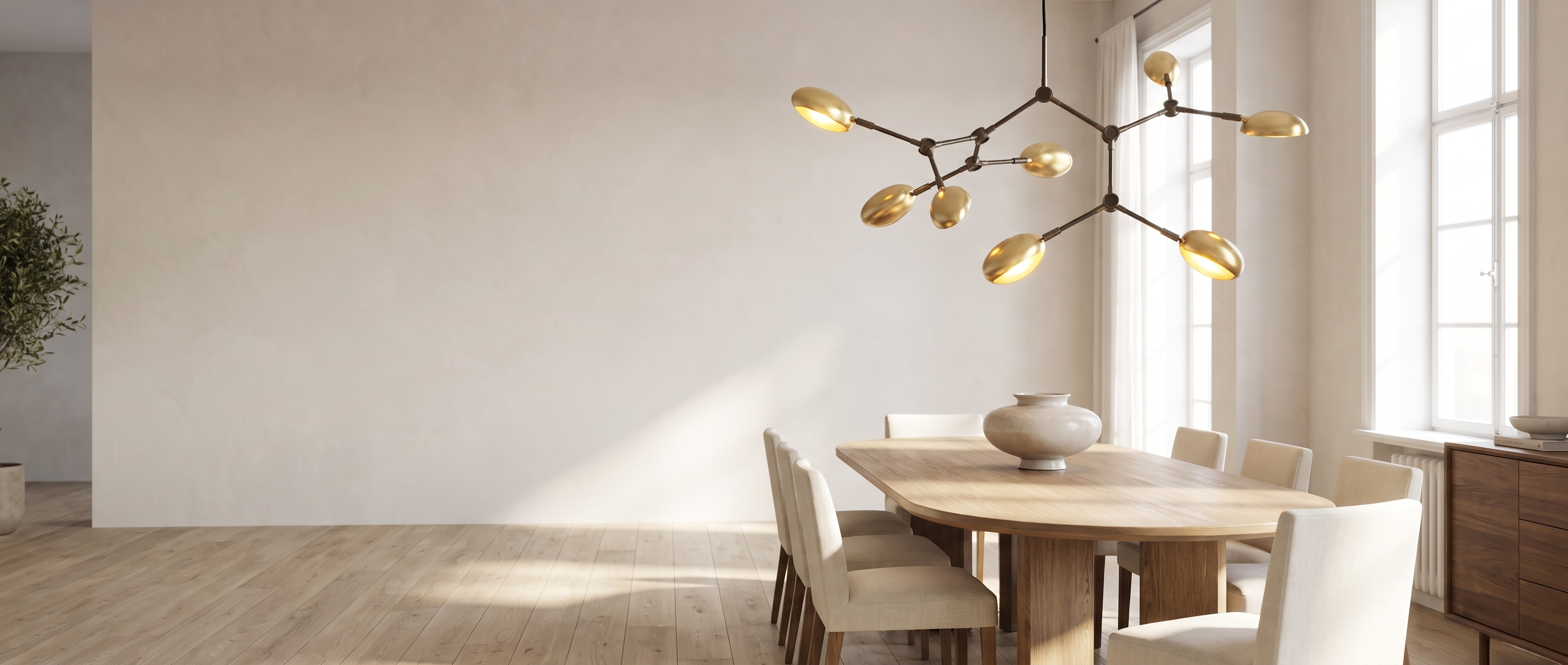 Ramo Goccia brass branch chandelier above a dining table in a bright dining room