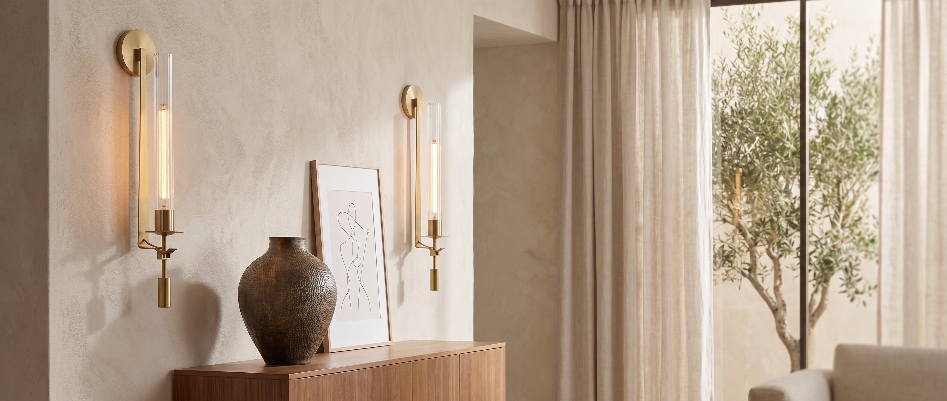 Gold ribbed glass wall sconces flanking a credenza in a sunlit living room